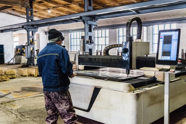 CNC lazer makinesinin operatörü. Fotoğraf fabrika katında çekildi.