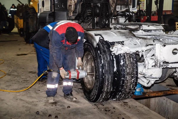 汽车修理工用气动扳手拆卸卡车的后轮 这张照片是冬天在一家卡车加油站拍的 — 图库照片