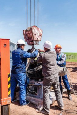 Orenburg, Rusya - 26 Mayıs 2020: İnşaat alanındaki işçiler bir vinç kancasına yükleme yapıyorlar