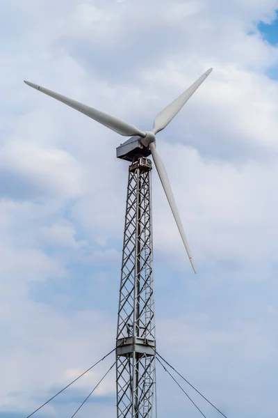 Wind turbine on a metal truss tower against a cloudy sky. The picture was taken in Russia, in the Orenburg region, in the countryside