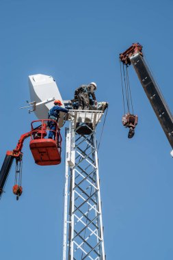 Havadaki işçiler vinç yardımıyla rüzgar jeneratörünün kurulumunu gerçekleştiriyorlar. Rusya, Orenburg bölgesi