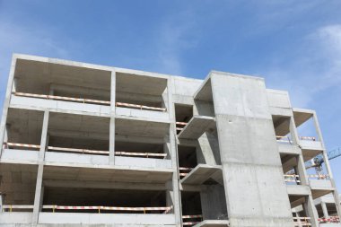 Yapısı açık ve mavi gökyüzü olan beton bina yapım aşamasında.