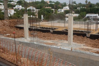 Çağdaş villaları olan bir banliyö mahallesinde, beton yapı ve metal takviyeli modern bir konut inşaatı.