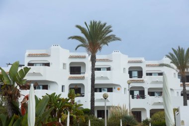 Beyaz Akdeniz tarzı, balkonları, palmiyeleri ve tropikal bitkileri olan bir apartman dairesi. Algarve, Portekiz