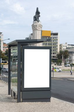 Blank advertising billboard at a bus stop in Marqus de Pombal Square, Lisbon, Portugal, with the iconic statue of Marqus de Pombal in the background.