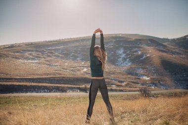 Genç kadın bir dağın tepesinde egzersiz yerleştirmek
