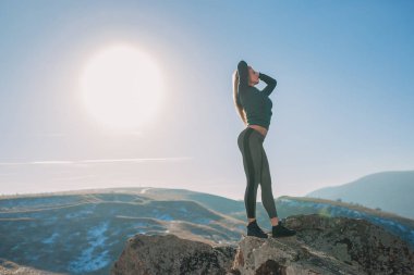 Genç kadın bir dağın tepesinde egzersiz yerleştirmek