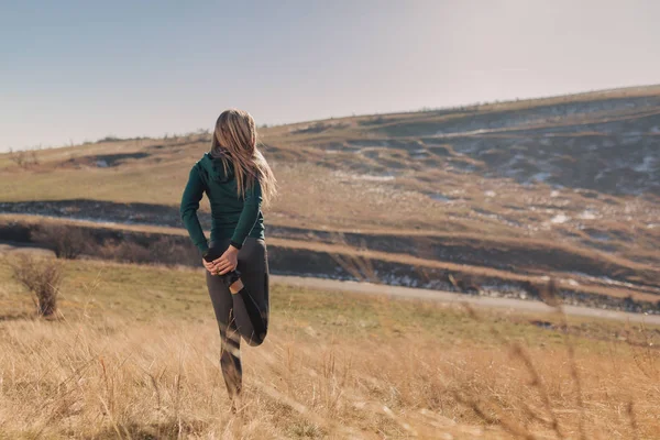 Genç kadın bir dağın tepesinde egzersiz yerleştirmek