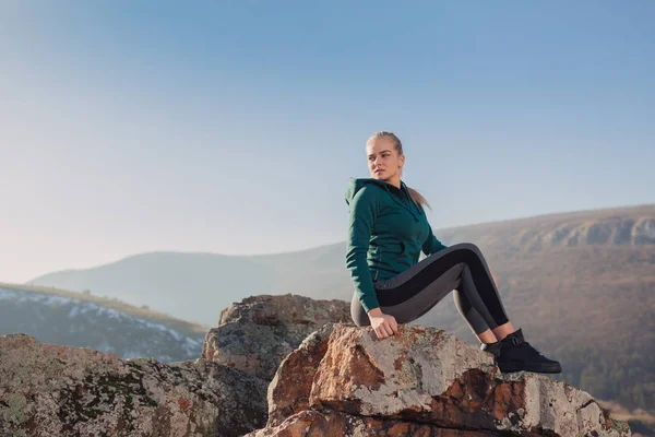Genç kadın bir dağın tepesinde egzersiz yerleştirmek
