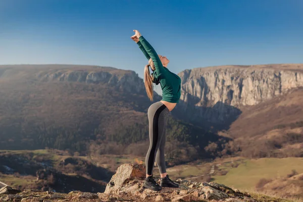 Genç kadın bir dağın tepesinde egzersiz yerleştirmek