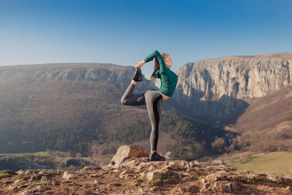 Genç kadın bir dağın tepesinde egzersiz yerleştirmek