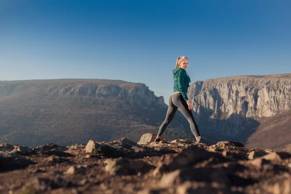 Genç kadın bir dağın tepesinde egzersiz yerleştirmek