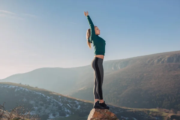 Genç kadın bir dağın tepesinde egzersiz yerleştirmek