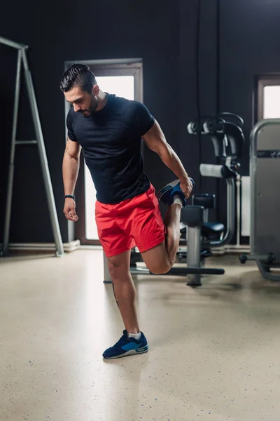 Strong bearded man in the gym stretching — Stock Photo, Image