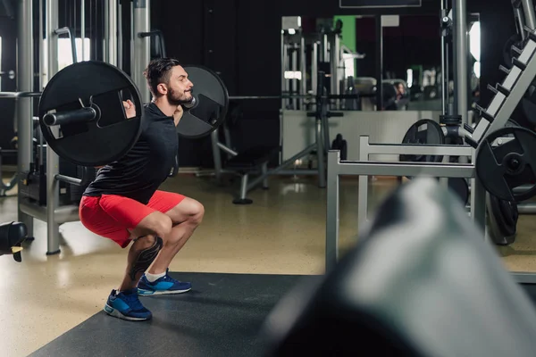 Strong man in the gym doing squats — Stock Photo, Image