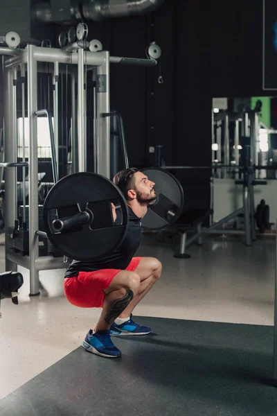 Strong man in the gym doing squats — Stock Photo, Image