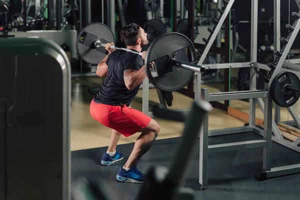 Strong man in the gym doing squats — Stock Photo, Image