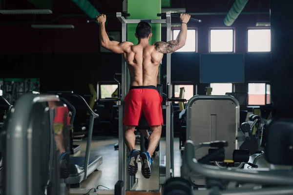 Strong man in the gym doing back exercise — Stock Photo, Image