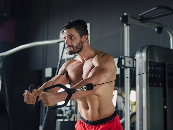 Сильный мужчина в спортзале делает упражнения на грудь — стоковое фото