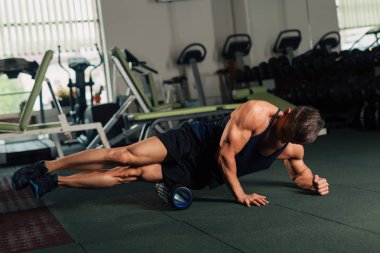 Genç adam spor salonunda bir kattaki haddeleme yerleştirmek