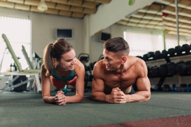 Genç mutlu çift planking yapmaya spor salonunda egzersiz yerleştirmek