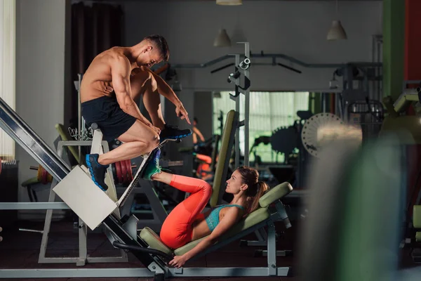 Young fit couple doing a legs press workout together — Stock Photo, Image