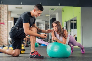 Spor salonunda kişisel antrenörü olan genç bir kadın.