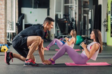 Spor salonunda kişisel antrenörü olan genç bir kadın.