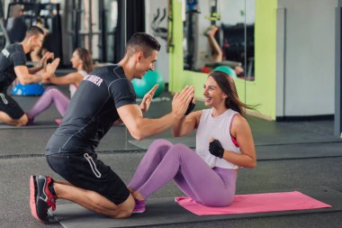 Spor salonunda kişisel antrenörü olan genç bir kadın.