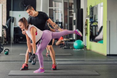 Spor salonunda kişisel antrenörü olan genç bir kadın.