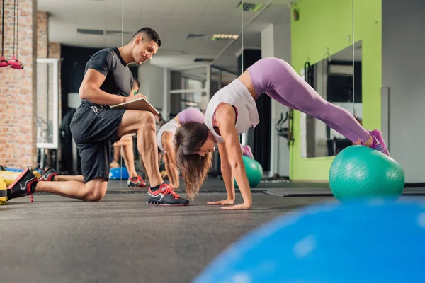 Spor salonunda kişisel antrenörü olan genç bir kadın.