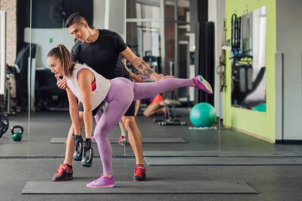 Spor salonunda kişisel antrenörü olan genç bir kadın.