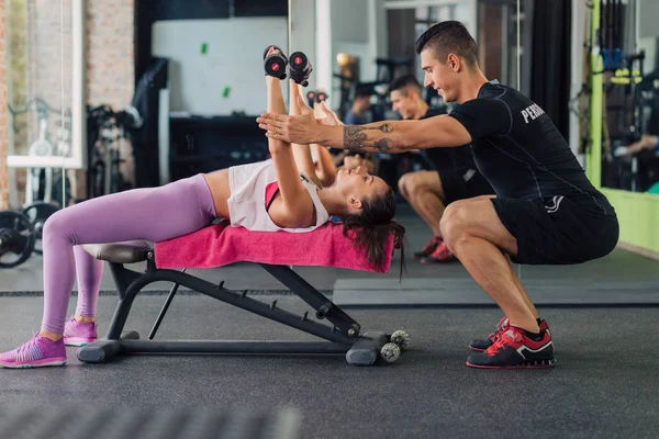 Spor salonunda kişisel antrenörü olan genç bir kadın.