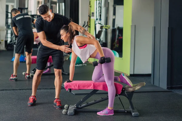 Spor salonunda kişisel antrenörü olan genç bir kadın.