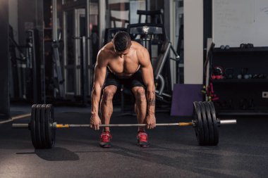 Spor salonundaki genç kaslı adam egzersiz yapıyor.