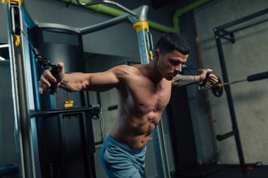 Spor salonundaki genç güçlü adam göğüs kafesi egzersizi yapıyor.