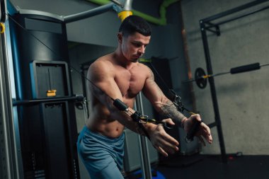 Spor salonundaki genç güçlü adam göğüs kafesi egzersizi yapıyor.