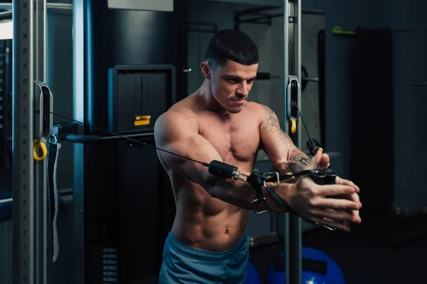 Spor salonundaki genç güçlü adam göğüs kafesi egzersizi yapıyor.