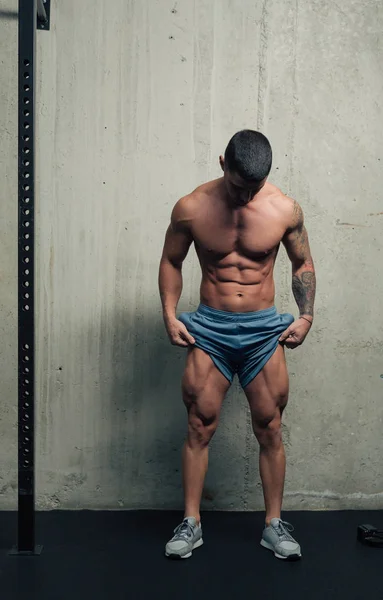 Genç güçlü adam poz veriyor ve kaslarını esnetiyor.