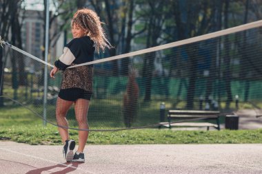 Voleybol sahasında poz veren çekici genç bir kadın.