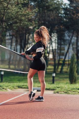 Voleybol sahasında poz veren çekici genç bir kadın.