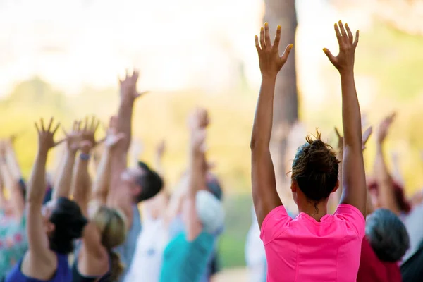 İnsanlar gün batımında parkta yoga yapıyor.