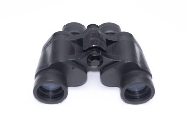 Uzak nesneleri görmek için kullanılan optik bir araç olan beyaz arkaplandaki siyah dürbünün yakın plan görüntüsü.