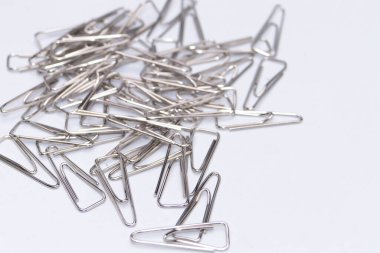 Yakın çekim, temiz, parlak beyaz bir arkaplan karşısında dağınık gümüş renkli saç tokaları gösteriyor..