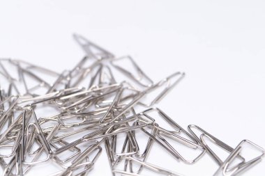 Temiz beyaz arka planda dağınık gümüş kağıt tokaların yakın plan çekimi, ofis malzemelerini ön plana çıkarıyor..