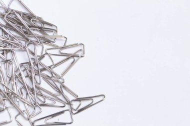 Temiz, beyaz bir arkaplana saçılmış gümüş metal kağıt tokaların yakın plan çekimi, minimalist ve organize bir estetik yaratıyor..