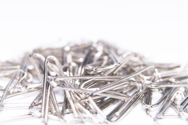 Beyaz bir yüzeye saçılmış gümüş ataç yığınının yakın çekim görüntüsü minimalist ve temiz bir kompozisyon oluşturur..