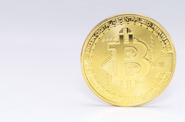 Beyaz bir yüzeyde duran parlak, altın bir Bitcoin 'in yakın çekimi. Kripto para birimi, yatırım ve dijital finans sunar.