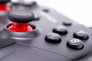 Kırmızı joystick ve A, B, X, Y tuşlarına odaklanmış siyah oyun kontrolörünün makro görüntüsü. Arkaplan bulanık, denetleyicilerin detaylarını vurguluyor.