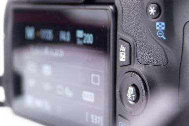 Siyah bir DSLR kameranın ayrıntılı görünümü, ekran ayarları ve bitişik düğmeler üzerinde odaklanır. Resim, kamera arayüzünü vurgular.